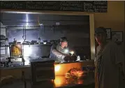  ?? STEVE EARLEY / THE VIRGINIAN-PILOT ?? Aaron Howe cooks in the dark kitchen Friday at the Island Convenienc­e Store in Rodanthe on Hatteras Island, N.C. A constructi­on company caused a power outage that forced tourists to evacuate.