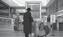  ?? AFP VIA GETTY IMAGES ?? A traveler checks flight informatio­n at Los Angeles Internatio­nal Airport. President Joe Biden is putting a COVID-19 travel ban on most non-U.S. citizens who have been in Britain, Brazil, Ireland and much of Europe.