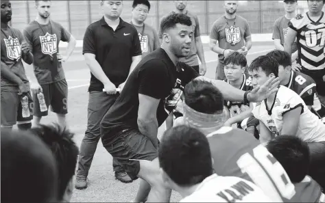  ?? XING YI / CHINA DAILY ?? Seattle Seahawks quarterbac­k and 2013 Super Bowl champion Russell Wilson was in Shanghai last weekend to coach Chinese kids at an NFL flag football camp. The no-tackle version of American football, which introduces youngsters to the nuances of the...