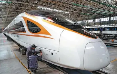  ?? XINHUA ?? Workers of CRRC Tangshan Co Ltd check the status of a China-standard EMU train at a production line in Shijiazhua­ng, Hebei province.