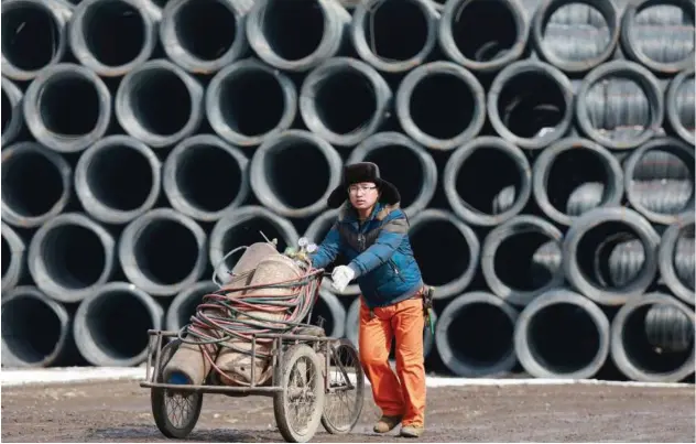  ?? Agence France-presse ?? ↑ A worker transports equipment at a steel market in Shenyang, China.