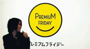  ?? Picture: REUTERS ?? MELLOW YELLOW: A woman in Tokyo, Japan, walks past the logo of the Premium Friday campaign, which encourages companies to let workers out a few hours early on the last Friday of every month