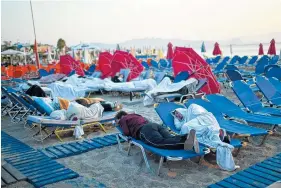  ?? THE ASSOCIATED PRESS ?? Tourists sleep on sun beds at a beach on the Greek island of Kos on Saturday.