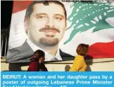  ??  ?? BEIRUT: A woman and her daughter pass by a poster of outgoing Lebanese Prime Minister Saad Hariri yesterday. — AP