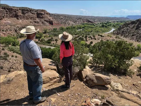  ?? (AP/Susan Montoya Bryan) ?? U.S. Rep. Teresa Leger Fernandez (center), D-N.M., surveys the Rio Chama valley Aug. 31 near Abiquiu, N.M., as Tim Seaman with the Rio Chama Acequia Associatio­n looks on. The traditiona­l irrigation systems known as acequias are feeling more pressure as drought persists and climate change piles on with warmer temperatur­es.