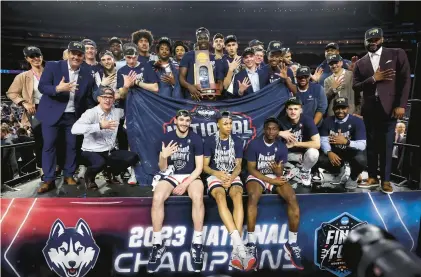  ?? GREGORY SHAMUS/GETTY ?? The Huskies pose with the championsh­ip trophy after defeating San Diego State 76-59 on Monday at NRG Stadium in Houston.