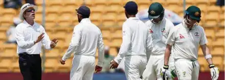  ??  ?? Virat Kohli (second from left) speaks to the umpire as Australia captain Steven Smith (right) walks off the ground after being dismissed in the Second Test on March 7.