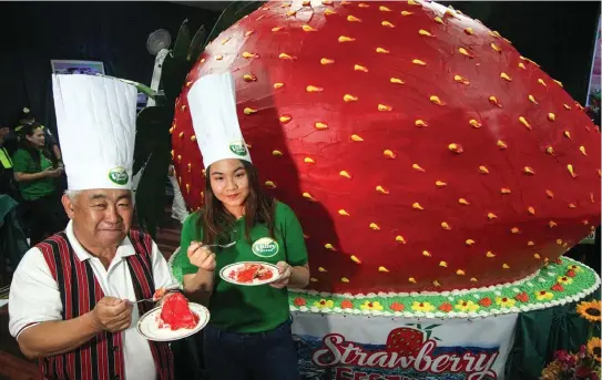  ?? Photo by Jean Nicole Cortes ?? CAKE FOR ALL. La Trinidad Mayor Romeo Salda and Valley Bread’s Angela Espadero partake of the giant strawberry cake weighing 1.6 tons served to 12,000 people March 23 at the Lednicky Hall.