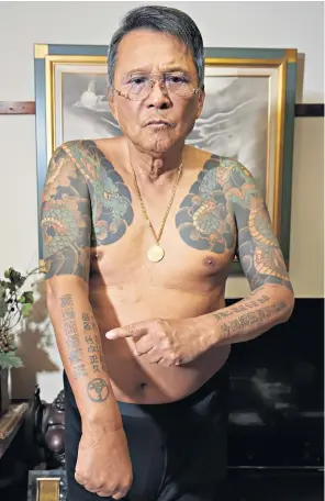  ?? ?? Tattooed former yakuza member Satoru Takegaki points to the name of his gang