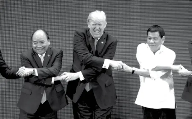  ?? (AP) ?? US President Donald Trump, center, reacts as he does the "Asean-way handshake" with Vietnamese President Tran Dai Quang, left, and Philippine President Rodrigo Duterte on stage during the opening ceremony at the ASEAN Summit at the Cultural Center of...