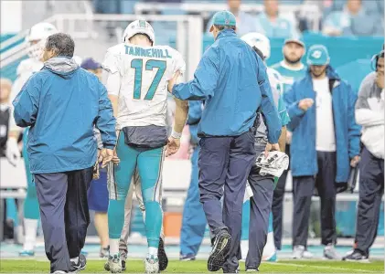  ?? ALLEN EYESTONE / THE PALM BEACH POST ?? Dolphins quarterbac­k Ryan Tannehill (center) limps to the sideline with assistance during the third quarter with what team offifficia­ls worried could be a torn ACL in his left knee. “It doesn’t look good,” coach Adam Gase said of the prognosis.