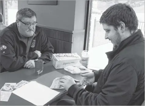  ?? CAROLE MORRIS-UNDERHILL ?? Veteran firefighte­r Greg Lake and Daniel Graham pore over old clippings as they discuss the events of Nov. 11, 1992.