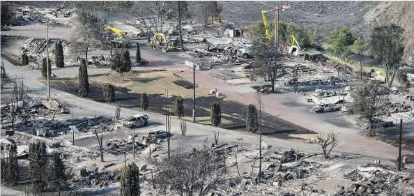  ?? — THE CANADIAN PRESS ?? B.C. Hydro workers repair power lines among the remains of mobile homes destroyed by wildfire in Boston Flats near Ashcroft on Sunday. B.C. government officials now estimate that 9,000 people have been evacuated from their homes due to wildfires.
