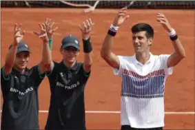  ?? CHRISTOPHE ENA — THE ASSOCIATED PRESS ?? Serbia’s Novak Djokovic and ball boys celebrate after his three set win, 6-3, 6-4, 6-2, over Spain’s Marcel Granollers in the first round match of the French Open tennis tournament at the Roland Garros stadium, in Paris, France. Monday.