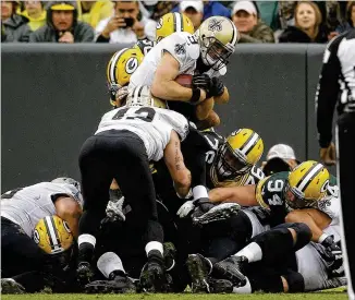  ?? JEFFREY PHELPS / AP ?? Saints QB Drew Brees goes over the pile for a 1-yard touchdown in Sunday’s 26-17 victory over the Packers at Lambeau Field. Brees also threw a touchdown pass, the 500th of his career.