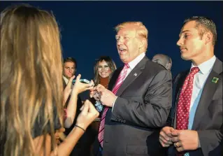  ?? GREG LOVETT / THE PALM BEACH POST ?? President Donald Trump and first lady Melania Trump (center) greet well-wishers Tuesday at Palm Beach Internatio­nal Airport as they arrived in South Florida from the White House.