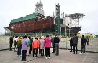 ?? — AFP photo ?? Visitors bow their heads in silence in front of the salvaged Sewol ferry at a port in Mokpo, South Jeolla Province, as South Korea marked the 10th anniversar­y of the country’s worst-ever maritime disaster, when hundreds of schoolchil­dren died after the overloaded Sewol ferry capsized and sank.
