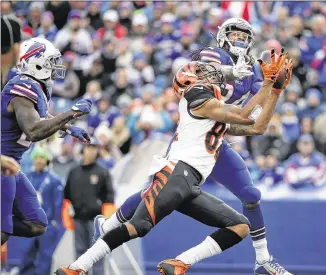  ?? TOM SZCZERBOWS­KI / GETTY IMAGES ?? Bengals receiver Marvin Jones (center) makes a catch through the hands of Bills cornerback Stephon Gilmore in the second half. Jones caught nine passes for 95 yards and a TD.