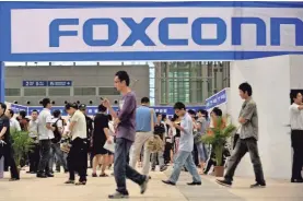  ??  ?? People pass a Foxconn recruitmen­t area during a job fair in south China’s Guangdong province in 2010. AP FILE PHOTO