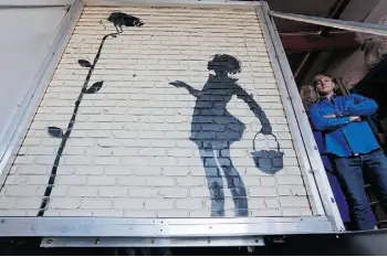  ?? REED SAXON/THE ASSOCIATED PRESS ?? Flower Girl, a delicate stencil on a massive brick wall by popular British street artist Banksy, was sold to an anonymous buyer for $209,000 US at an auction in Beverly Hills this week.