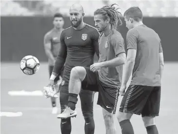  ?? MARK RALSTON/GETTY IMAGES ?? Tim Howard, left, watches as midfielder Kyle Beckerman warms up. Howard will start at goalkeeper Saturday for the U.S.
