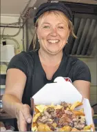  ?? ERIC MCCARTHY/JOURNAL PIONEER ?? Kelly Wilson serves up the day’s special – cheeseburg­er poutine topped off with fried pickle chips – from her fry truck, Up West Fire Fries.