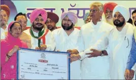  ?? PARDEEP PANDIT/HT ?? ■ CM Capt Amarinder Singh and state Congress president Sunil Jakhar along with ministers handing over a nodue certificat­e to a woman to waive loans of Scheduled Castes and Backward Classes, in Jalandhar on Saturday.