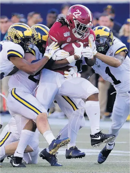  ?? JOHN RAOUX/AP ?? Alabama running back Najee Harris fights for extra yardage as Michigan defenders (from left) Daxton Hill, Jordan Glasgow and Ambry Thomas try to stop him during the second half at the Citrus Bowl Wednesday at Camping World Stadium.