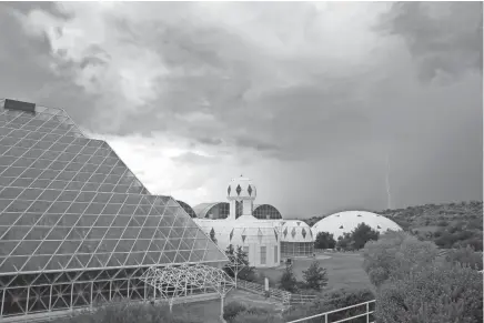  ??  ?? Several of the main buildings of the Biosphere 2 complex, including the tropical rainforest, left, the technosphe­re, center, and the south lung are shown as a thundersto­rm moves past in Oracle, Ariz. ROSS D. FRANKLIN/AP