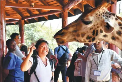  ?? XINHUA ?? A Chinese tourist looks at a giraffe in Nairobi, the capital of Kenya.