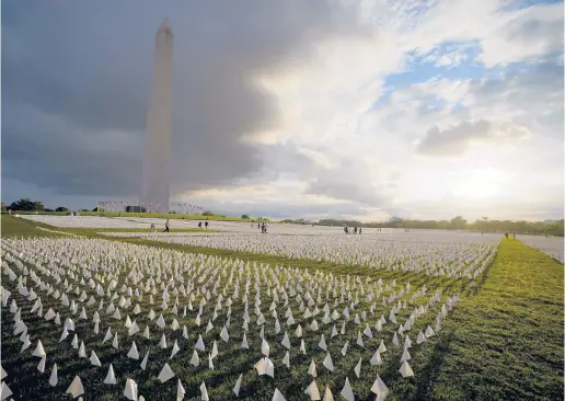  ?? BRYNN ANDERSON/AP 2021 ?? Visitors gaze at white flags, part of a temporary art installati­on in remembranc­e of Americans who died of COVID-19, in Washington. A U.S. program offers up to $9,000 per funeral for COVID-19 related deaths. The virus death toll in the U.S. tops 966,000.