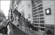  ?? AP/CHRISTOPHE ENA ?? Workers remove wooden planks from shop windows on the Champs-Elysees avenue in Paris on Sunday as stores reopened after Saturday’s protests.