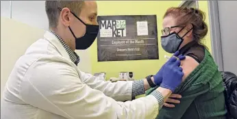  ??  ?? Pharmacist Richard Pachucki administer­s a COVID-19 vaccine to Cheryle Harbour of Menands at the Clifton Park Market 32.