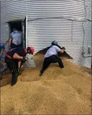  ?? ASSOCIATED PRESS ?? In this May 30photo provided by the Ross Township Fire Department, rescue personnel shovel soybeans out of the bottom of a bin during an effort to rescue farmer Jay Butterfiel­d, who was buried up to his neck inside.