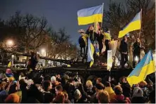  ?? Markus Schreiber/Associated Press ?? People wave Ukrainian flags as they stand atop a wreck of a Russian T-72 tank, destroyed on the approach to Kyiv and placed in front of the Russian Embassy in Berlin.