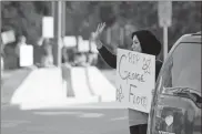  ?? Jeremy Stewart ?? Mariam Samha, a board member for AMP Rome — Art. Music. Purpose. — waves to passing vehicles Tuesday evening on Broad Street as she holds a sign in honor of George Floyd, the 46-year-old black man who died after being forcibly restrained by police in Minneapoli­s last week.