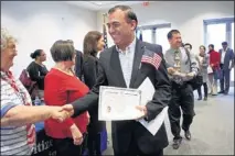  ??  ?? Rooziman Shah is congratula­ted by members of the Daughters of the American Revolution after he is sworn-in. Shah, who lives in Colliervil­le, was born in Pakistan. He is one of 248 who became naturalize­d citizens during Wednesday’s ceremony.