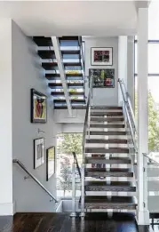  ?? Julie Soefer ?? The stairwell is lined with art against light neutral grays by Sherwin-Williams.