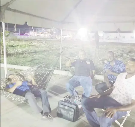  ?? (Photo taken from Gerald Forde Facebook page) ?? Liberty and Justice Party Leader Lenox Shuman (left) in his hammock accompanie­d by other party representa­tives at the Arthur Chung Convention Centre last night where they guarded the ballot boxes pending a recount.