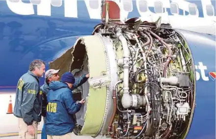  ?? REUTERS PIC ?? United States National Transporta­tion Safety Board investigat­ors examining the damaged engine of a Southwest Airlines plane on Tuesday.