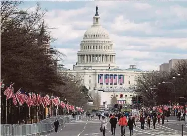  ?? AFP PIC ?? People walking near the US Capitol, between fences set up for the upcoming inaugurati­on in Washington.