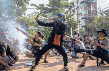  ?? THE NEW YORK TIMES ?? Protesters use slingshots March 28 during a clash with security forces in the Thaketa township of Yangon, Myanmar. Slingshots are the most popular of the homemade weapons wielded by protesters against the military junta.