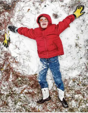  ?? Brett Coomer / Houston Chronicle ?? Zach Arnold tries to make a snow angel while playing in light snow that fell in Spring on Tuesday, when unusually low temperatur­es and a mix of precipitat­ion brought the area to a standstill.