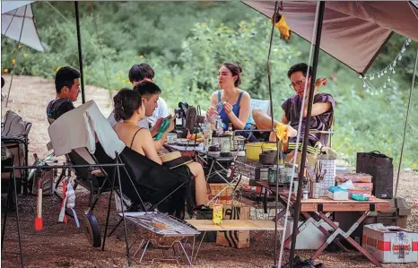  ??  ?? From left: Campers relax at a Treeline Camp near Songlin Lake in Anji county of Zhejiang province. Dazou enjoys a cup of coffee outside her tent at a campsite.