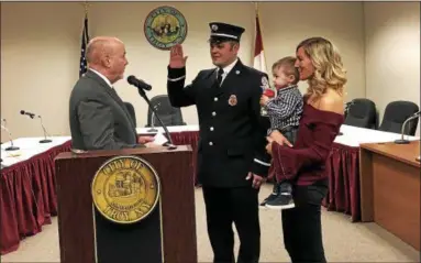  ?? NICHOLAS BUONANNO — NBUONANNO@TROYRECORD.COM ?? Troy Mayor Patrick Madden swears in firefighte­r David Bader — shown with his wife, Vincenza, and son, Vincent — as Bader gets promoted to captain.