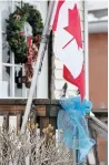  ??  ?? A blue ribbon tied to a front porch beneath a Canadian flag, in remembranc­e of Sgt. Andrew Harnett.