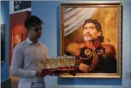  ?? DMITRI LOVETSKY — THE ASSOCIATED PRESS FILE ?? In this Wednesday file photo, a waiter carries drinks past a portrait of Argentine soccer legend Diego Maradona, part of the “Like The Gods” exhibition at the Museum of the Russian Academy of Arts in St. Petersburg, Russia.