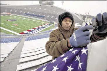  ?? BRANDON DILL/SPECIAL TO THE COMMERCIAL APPEAL FILES ?? Michael Parker hangs an American flag around the top of Liberty Bowl Memorial Stadium before the Iowa State-Tulsa Liberty Bowl. Memphis Convention & Visitors Bureau president Kevin Kane says, “The Big 12 would take us to a different level.”