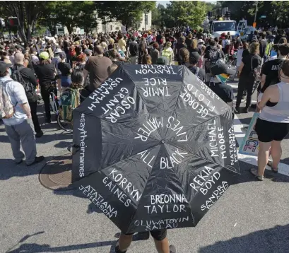  ?? PAUL CONNORS pHOTOS / BOSTON HERALD ?? IN THE STREETS: A Black Lives Matter protester carries an umbrella with the names of victims written on it prior to a city march on Saturday.