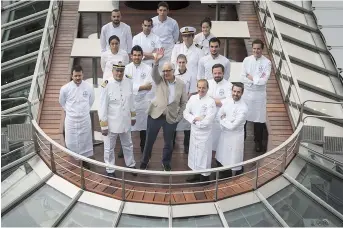  ??  ?? French master chef Alain Ducasse (center) waves as he poses with his team on his new boat restaurant. Ducasse, who has won 21 Michelin stars — more than any other chef alive — will be dishing up lobster and duck foie gras onboard his electric boat on the River Seine from September 10. — AFP